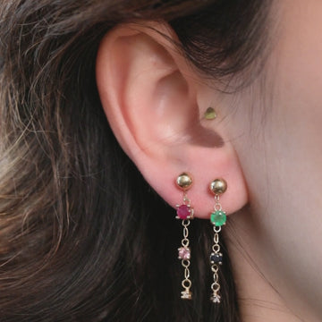 Video of the Emerald Cascade charm suspended from a gold stud earring, highlighting its delicate movement and natural gemstones.