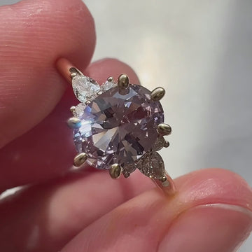 Close-up video of a lilac sapphire engagement ring with diamond accents in 14k yellow gold, handmade by Maksym Jewelry and shown worn on the hand. Filmed in natural light to highlight the gem’s soft purple hue and refined sparkle. Ruby Mardi, Montreal.