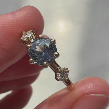 Video of the Isabella ring worn and in close-up, featuring a light blue sapphire flanked by white diamonds, set in yellow gold. The soft shimmer of the stones and warm glow of the metal are captured as the ring catches the light. Designed by Maksym Jewelry, available at Ruby Mardi.








