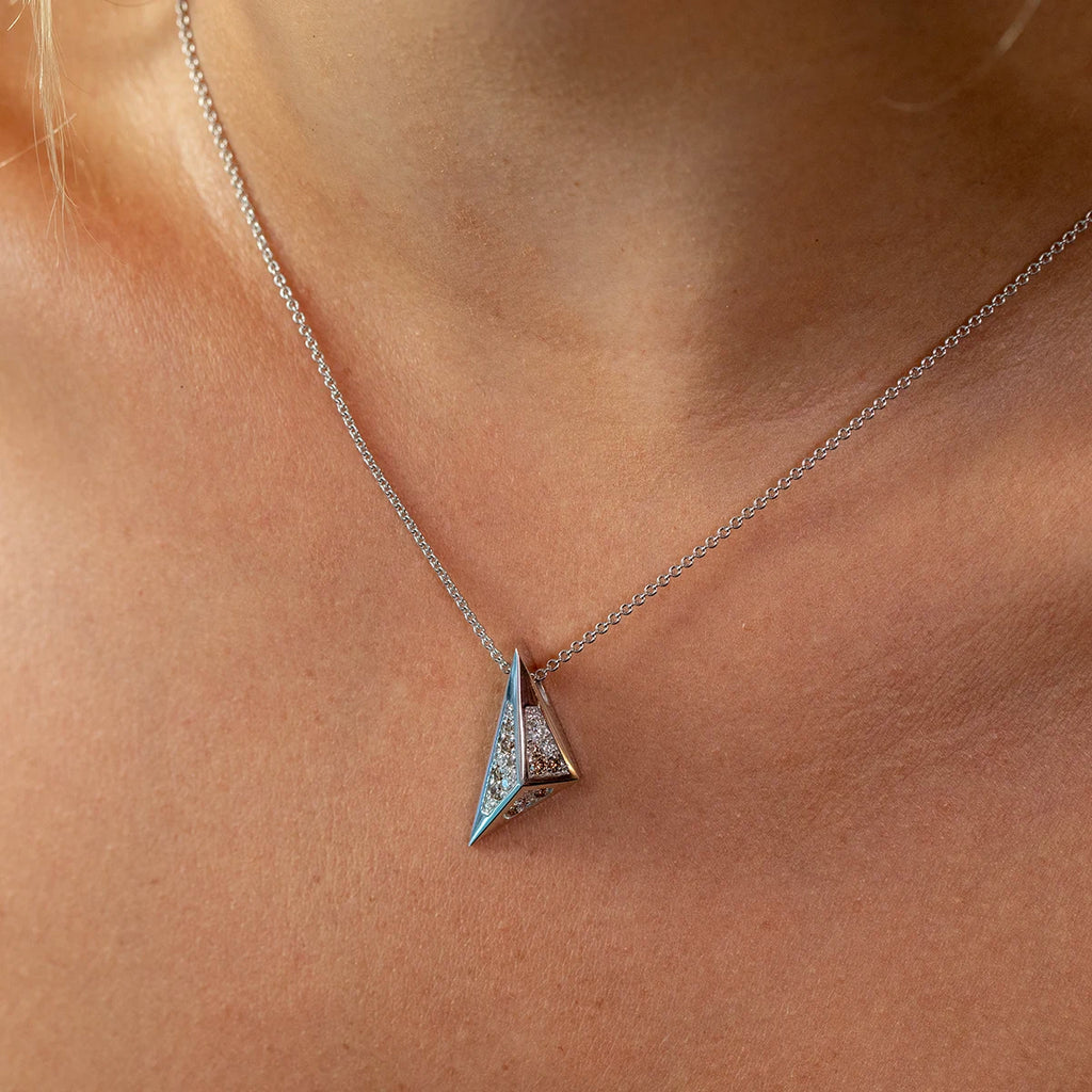 Ruby Mardi contemporary jewelry – Bena Jewelry Diamond Pyramid Pendant in 14k white gold, shown worn close-up on the neckline. Bold angular design with geometric pyramid shape, set with sparkling white diamonds and golden-brown diamonds for a modern, edgy unisex look.