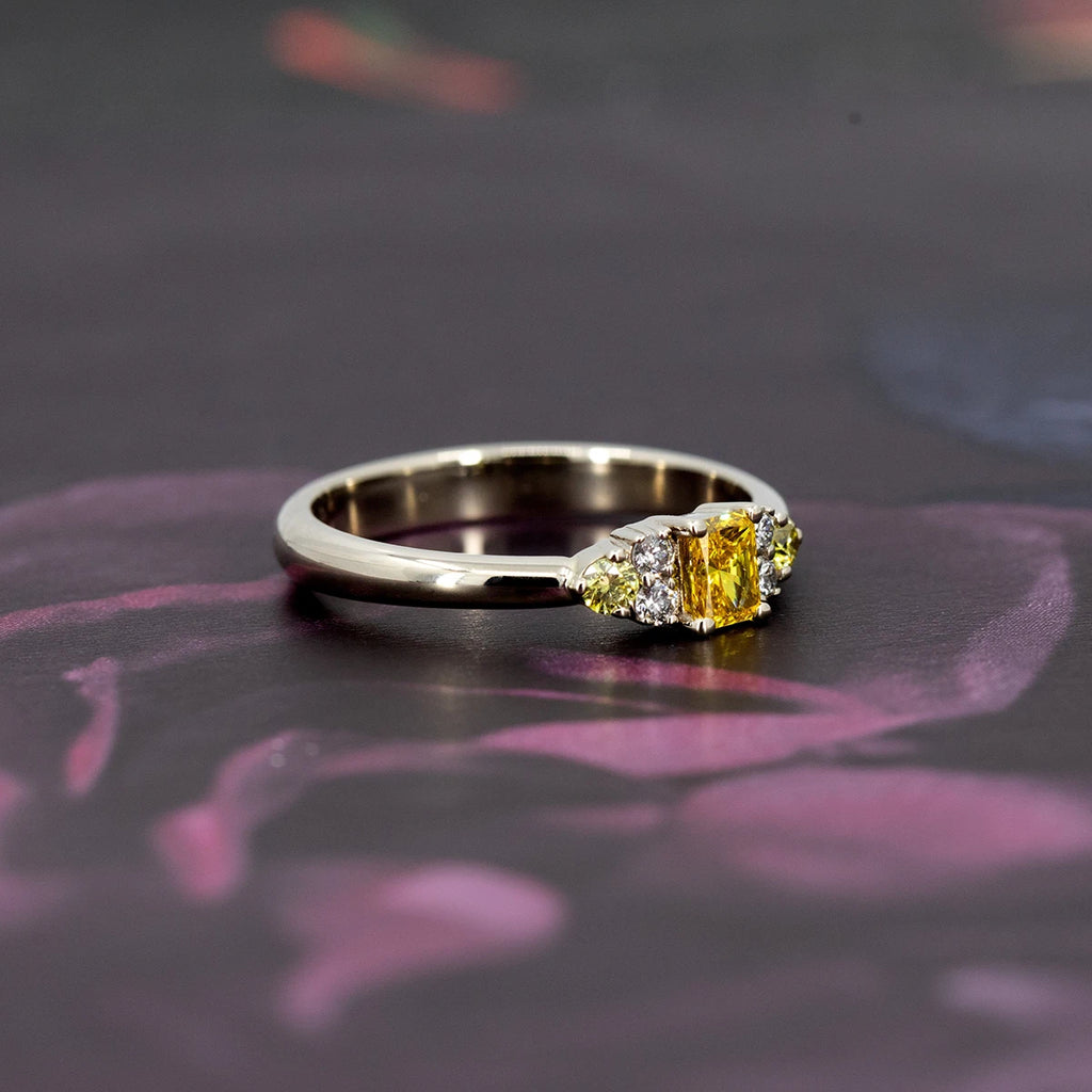 Radiant yellow lab-grown diamond ring with canary yellow and white diamond accents in 10k white gold, displayed on a dark floral background – Ruby Mardi Montreal.