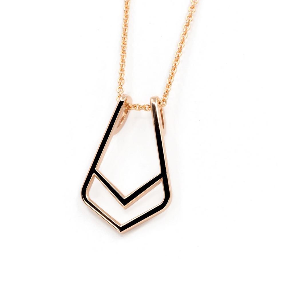 Chic Tie pendant by Bena Jewelry in rose gold, featuring a geometric openwork design. This modern statement piece doubles as a ring holder, combining elegance and functionality. Photographed against a clean white background, highlighting its polished finish. Available at Ruby Mardi, a collective of independent designer jewelry in Canada.







