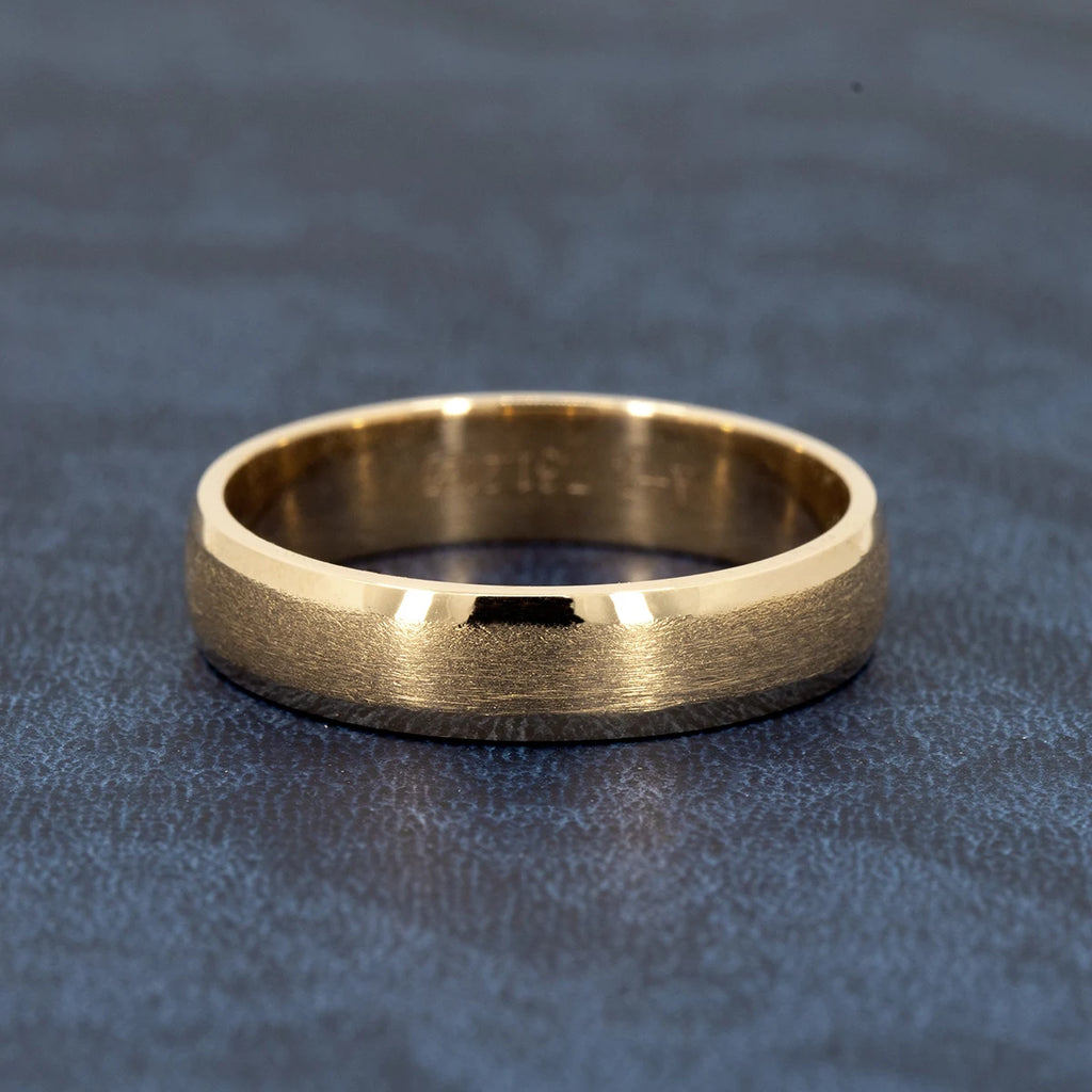 Yellow gold wedding band with matte center and polished edges, 5.5mm wide, handcrafted by Ruby Mardi Jewelry, displayed on textured blue background.

