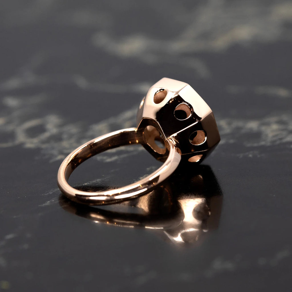 A side view of a handcrafted octagon smoky quartz cocktail ring by Bena Jewelry, showcasing its intricate rose gold bezel with geometric cutout details. The polished finish and unique design highlight the artisan craftsmanship, available exclusively at Ruby Mardi.