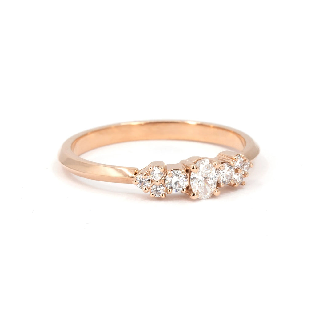 Side view of a rose gold ring featuring an oval center diamond, flanked by round accent diamonds arranged in a soft floral-inspired arc. Handmade in Montreal by Ruby Mardi.









