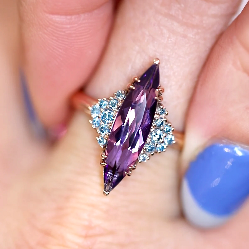 Large marquise-cut amethyst ring with clusters of lab-grown blue diamond accents, set in a 10k rose gold band, worn on a hand – Bena Jewelry, Ruby Mardi Montreal.