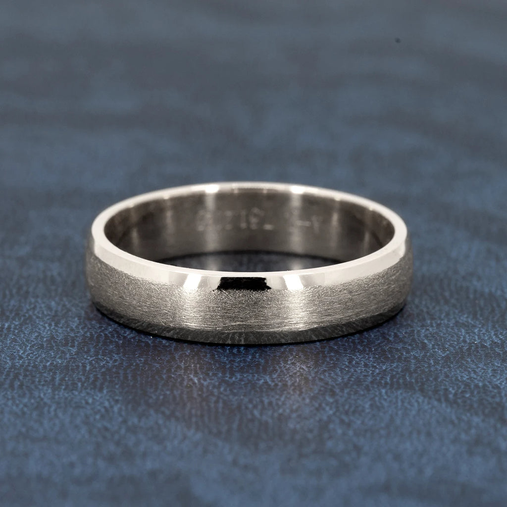 White gold wedding band with a matte center and polished edges, 5.5mm wide, unisex design by Ruby Mardi Jewelry, shown on a textured blue background.
