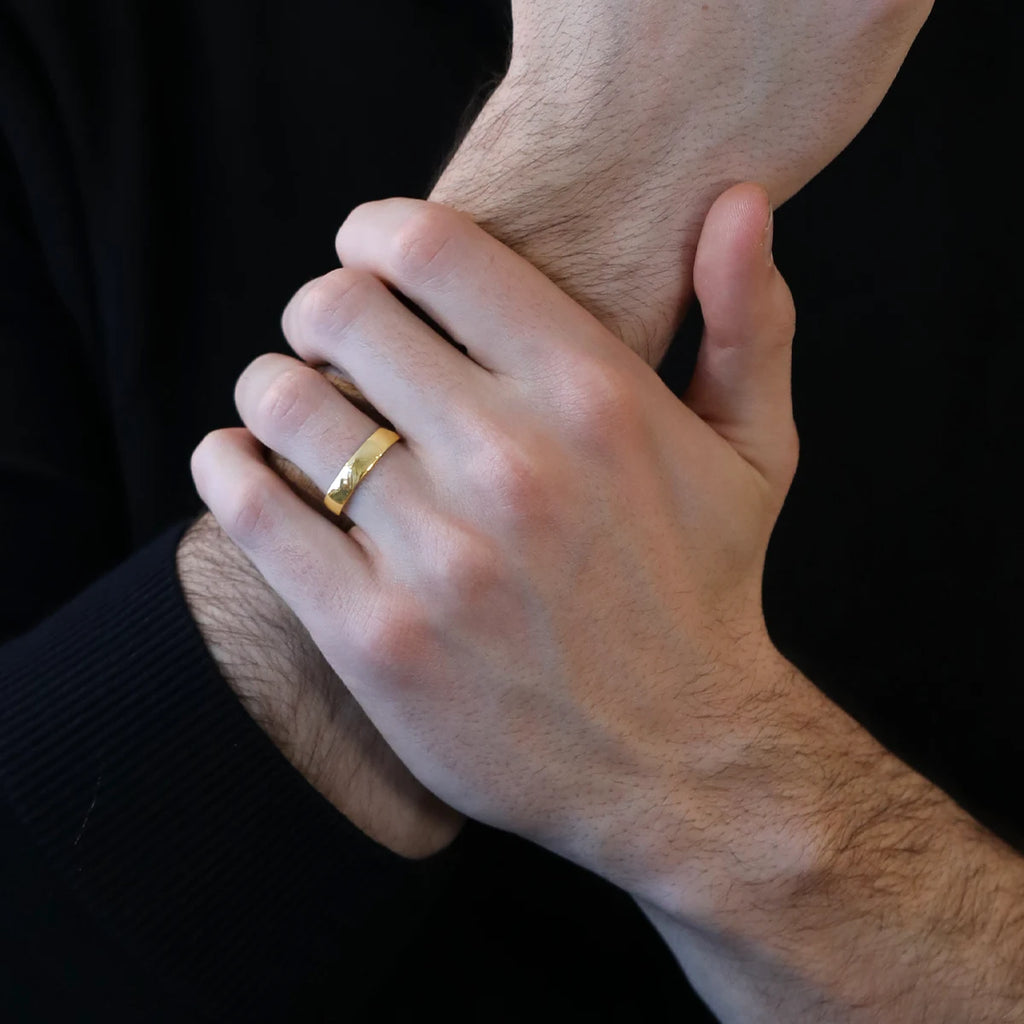 Man wearing a yellow wedding band with a rounded and minimalist style. Handmade in Montreal, these bridal rings are custom-made in gold at the Ruby Mardi jewelry store, a specialist in independent Canadian designer jewelry.