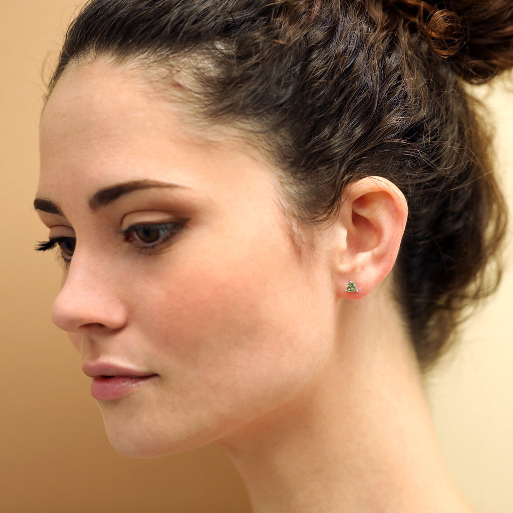 Girl wearing a gold stud earrings with green sapphire gemstone stud earrings 