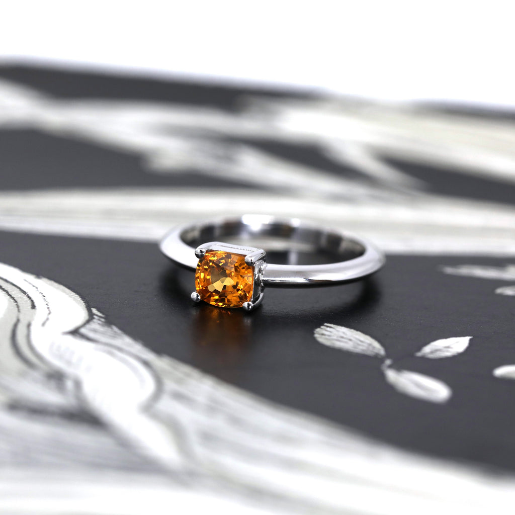 orange spessartite cushion cut garnet white gold bridal engagement ring custom made in montreal by ruby mardi jeweller in little italy on a dark background