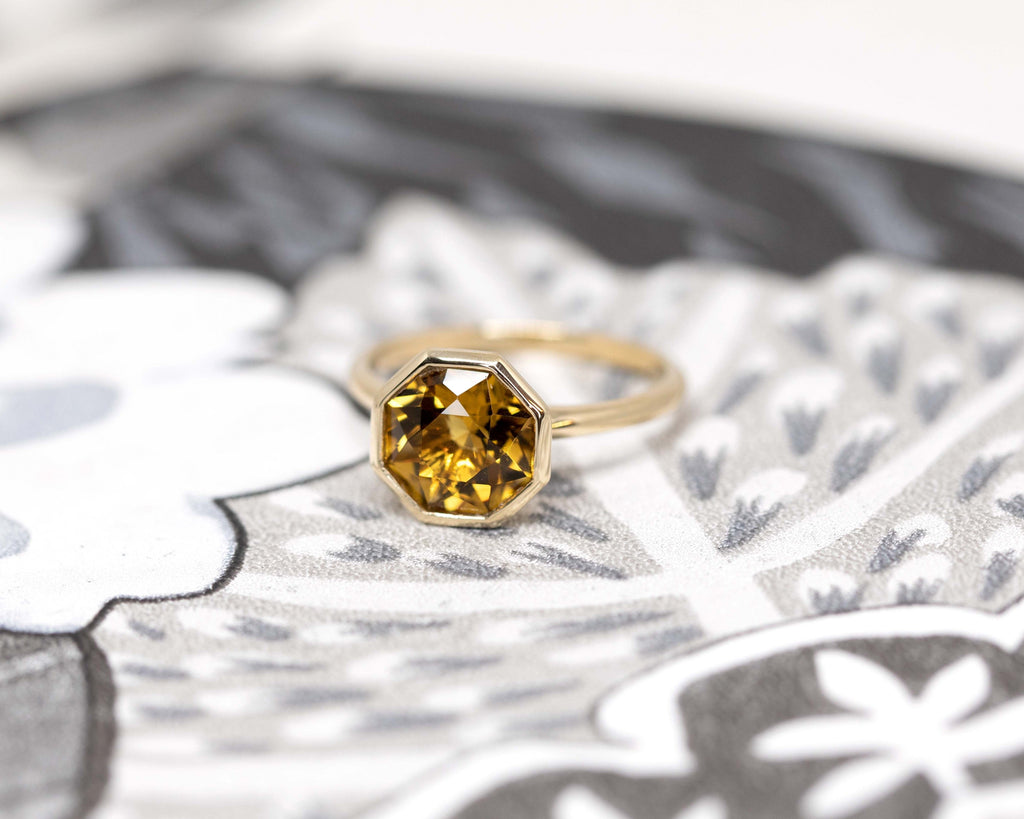 top view of fancy shape citrine gemstone bezel setting yellow gold ring custom made in montreal by boutique ruby mardi best jewelry store in montreal of canadian jewellery designer and one of the kind jewels on white and grey background