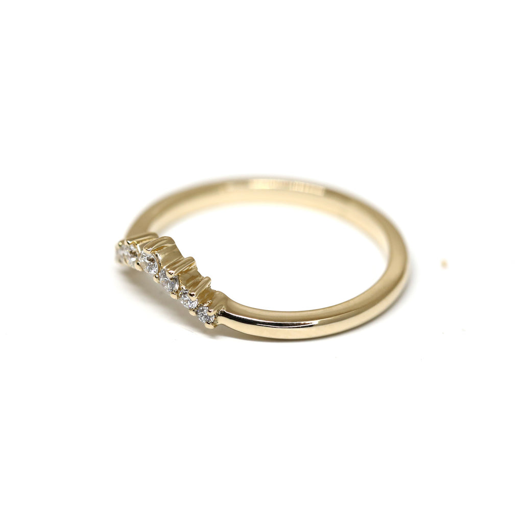 Side view on a delicate dainty yellow gold diamond band by Yuliya Chorna on a white background. Available at Ruby Mardi, a high end jewelry store showing the most talented Canadian jewellery designer. 