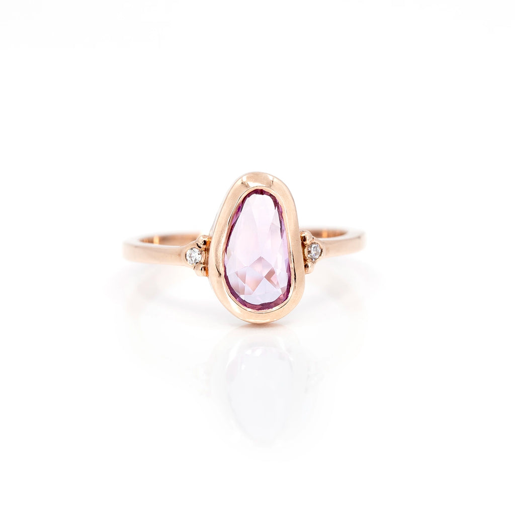 Fancy shape pink sapphire designer engagement ring custom made in Montreal by Arsaeus Designs, a Canadian brand of fine bespoke jewelry. This one-of-a-kind alternative bridal ring is set in rose gold and also features two round brilliant diamonds on the the band. 