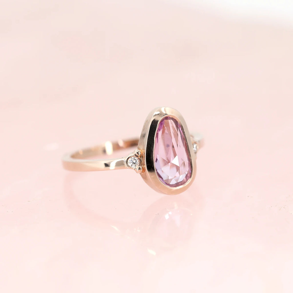 Bezel set rose gold fancy shape pink sapphire and diamond alternative engagement ring handmade by Arsaeus Designs for boutique Ruby Mardi in Montreal. This fine jewellery store sells the work from independant Canadian designers and one-of-a-kind engagement rings in Montreal.