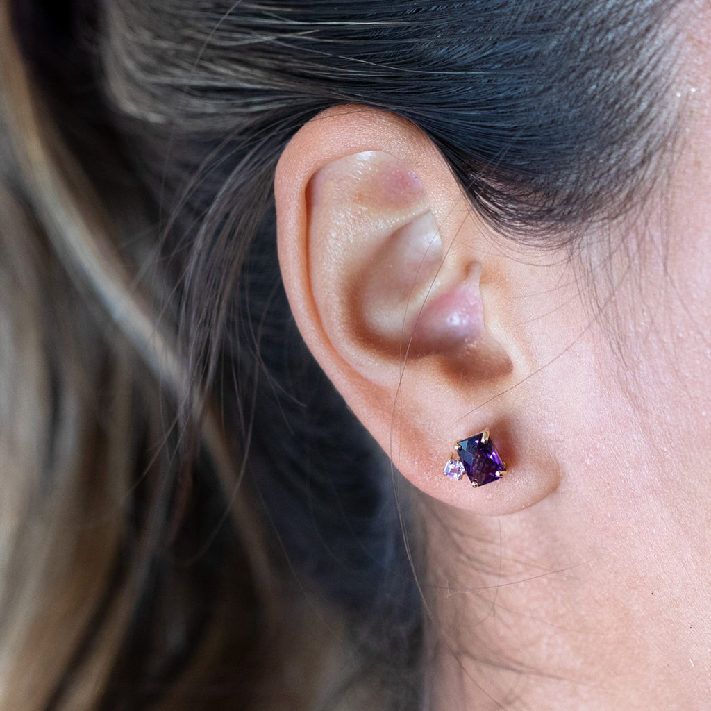 Gros plan sur une oreille portant une jolie boucle d'oreille avec pierres précieuses fabriquée à la main par la bijouterie Ruby Mardi à Montréal. Saphir rose et améthyste. 