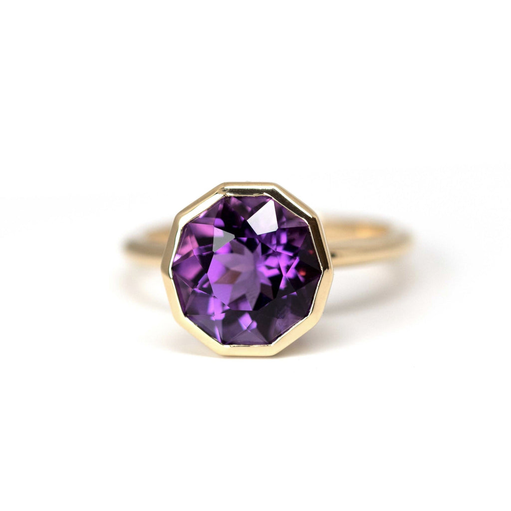 Statement ring in yellow gold with a large hexagonal amethyst gemstone with a deep purple color. This edgy piece of jewelry is made in Canada by jewelry designer Bena Jewelry. This fine and edgy jewel is available at Montreal's best jewelry store Ruby Mardi in Little Italy.