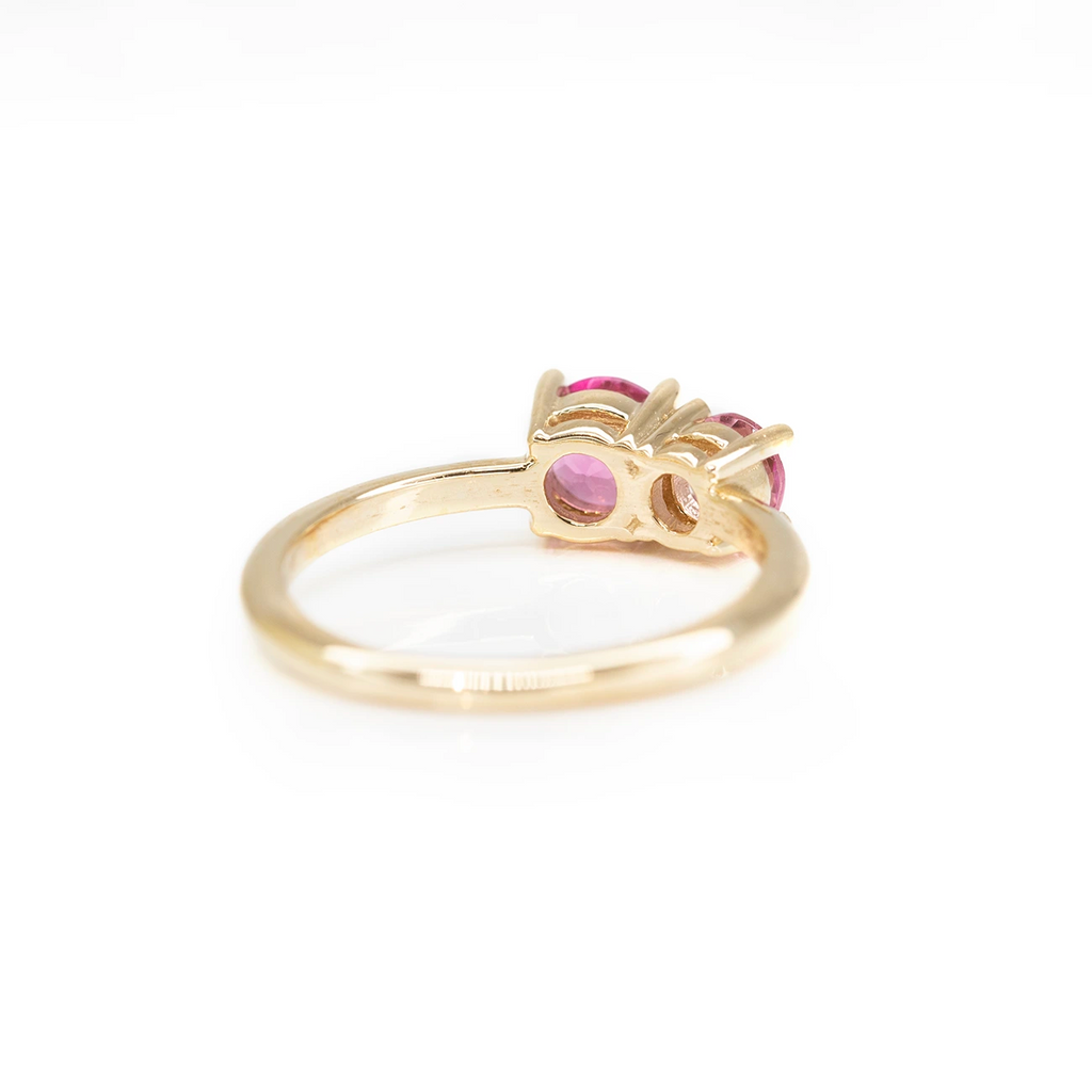back view of yellow gold toi et moi colored gemstone bridal ring custom made in montreal by lico jewelry store boutique ruby mardi designer gallery and jeweler on a pink background