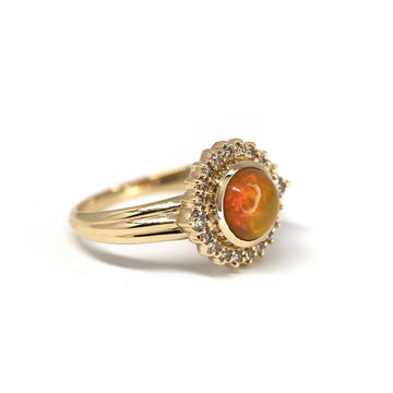 Product photography of ELENA : a beautiful ring in 14k yellow gold with a big orange opal and a cognac diamond halo, by Bena Jewelry. Find the most exquisite designer jewelry at Ruby Mardi, a fine jewelry store in Montreal that presents the work of the most talented Canadian jewelry designers. Custom jewelry services also offered.