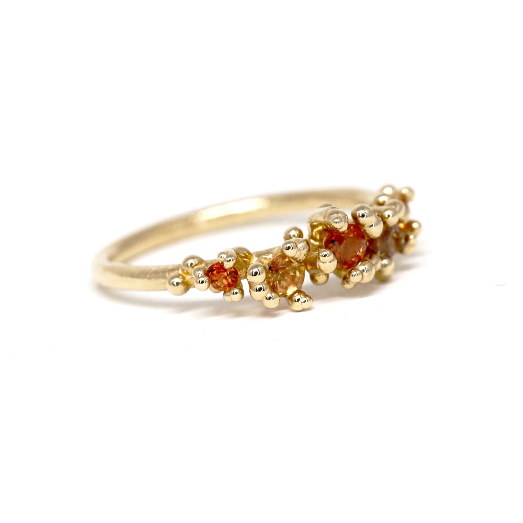 Areia ring over flowers by Toronto-based jewelry designer Meg Lizabet. Organic ring with hand-placed gold granules. 14K yellow gold ring with encapsulated orange, red and pink sapphire. Unique ring that cannot be reproduced. Find Meg Lizabet's creations in Montreal at Ruby Mardi, a boutique-gallery in Montreal's Little Italy, not far from Rosemont, Villeray, Outremont, Mile End. Custom jewelry design services in Montreal also available.