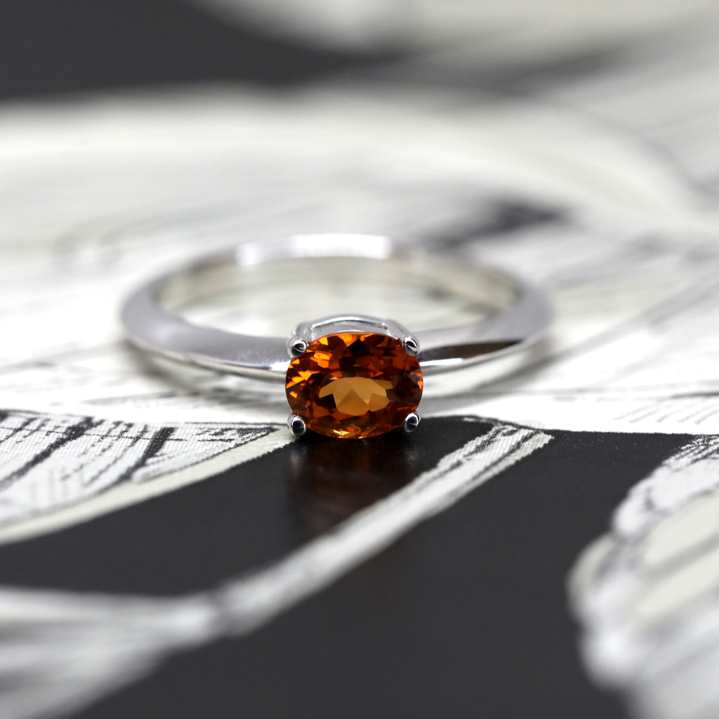 white gold bridal ring with natural orange garnet gemstone on a dark background