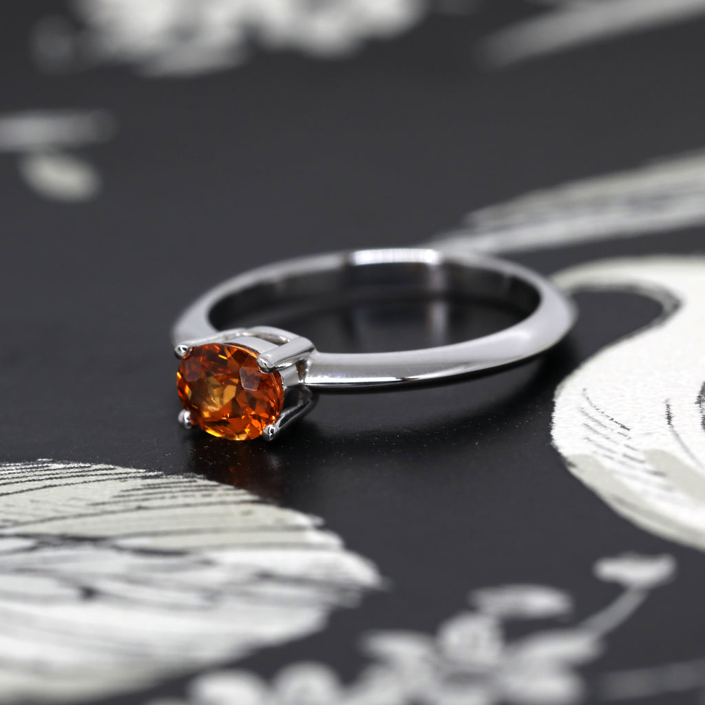side view of orange garnet oval shape natural gemstone engagement ring ruby mardi on a dark background