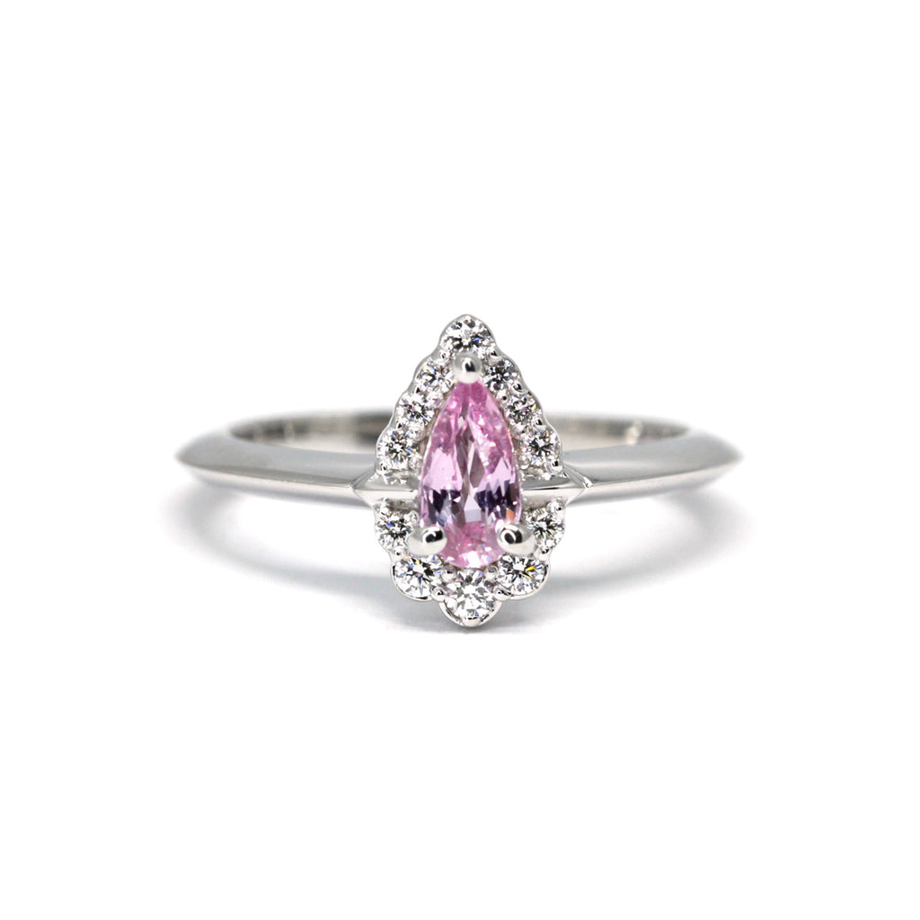 Pear Shape Pale Royal Pink Sapphire Engagement ring with a diamond halo on a white background by Ruby Mardi, a fine jewelry gallery in Montreal Little Italy, close by Bijouterie Italienne, and Rosemont, Outremont, Villeray, Parc Extension, Mile End, Mile Ex districts. White gold gemstone ring, bridal jewelry, wedding ring, ethical gem. Ruby Mardi offers custom jewelry services in Montreal. Lab grown diamonds, natural diamonds, Canadian diamonds, ethical diamonds, ethical gemstones.