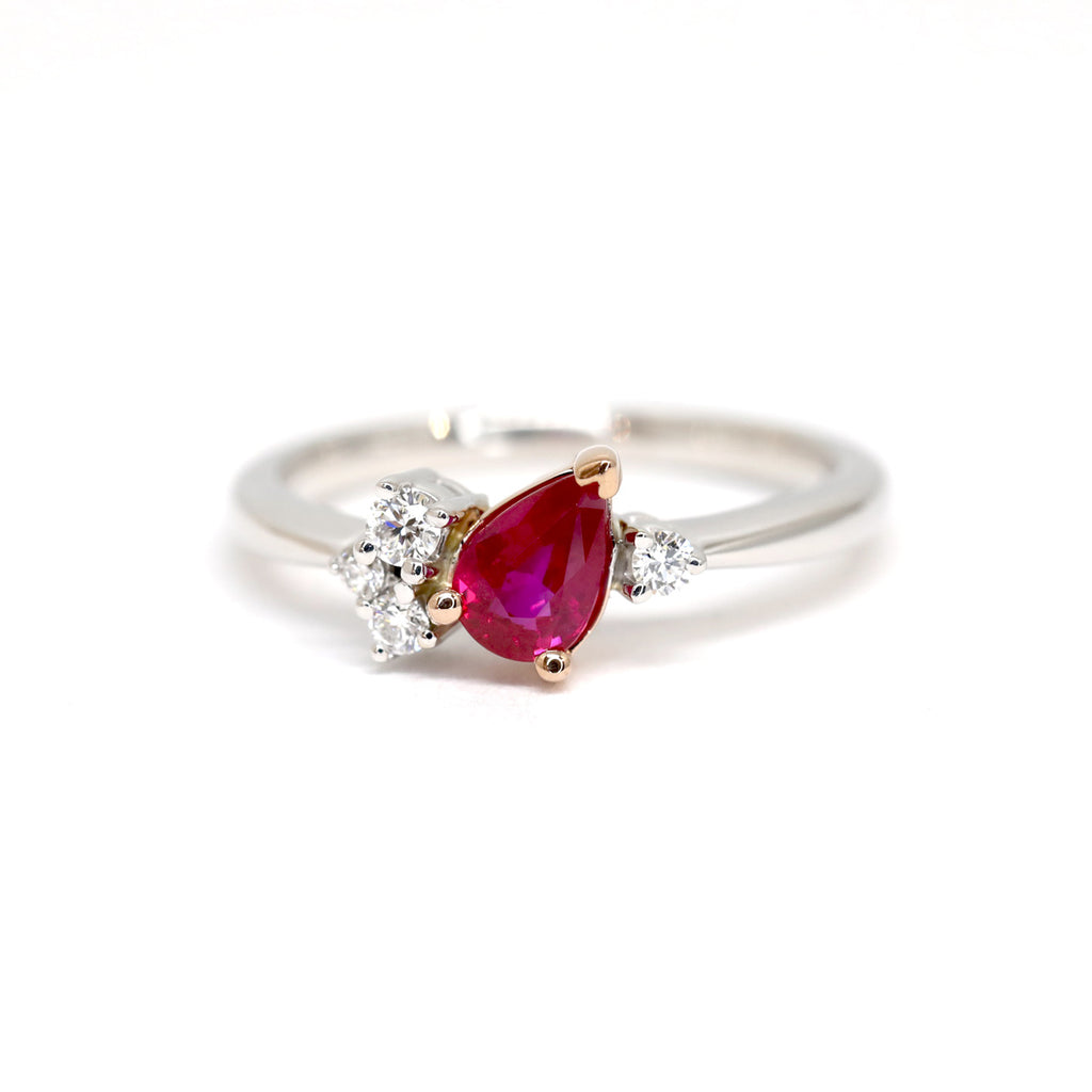 A bridal jewel photographed on a white background. The engagement ring is set in white gold and rose gold and features a natural pear shape ruby with natural diamond accents placed asymmetricaly. The wedding ring was handmade by Justine Quinal and is available only at Ruby Mardi, a cool jewelry store in Montreal.