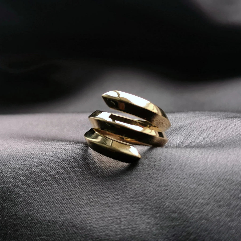 La bague Embrace en or vermeil du créateur de bijoux canadien Bena Jewelry, photographiée sur un tissu satiné. Bijou moderne et prédominant fabriqué à la main disponible à la bijouterie fine Ruby Mardi, en ligne ou dans la Petite Italie de Montréal.
