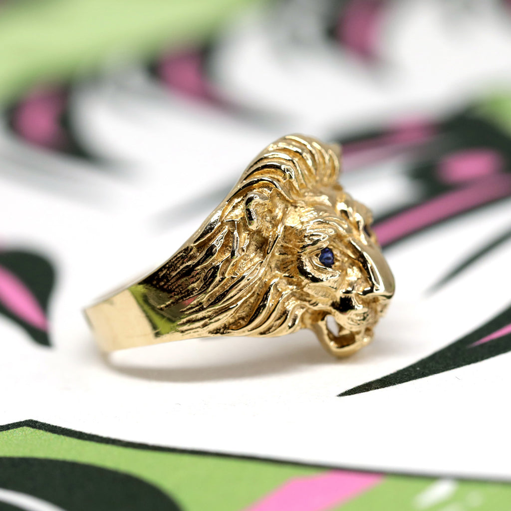 Vue de côté d'une bague en or en forme de tête de lion et yeux en saphirs bleus par la créatrice de bijoux Lico Jewelry. Ses créations sont disponibles chez Ruby Mardi, une bijouterie de luxe située dans la Petite Italie de Montréal.