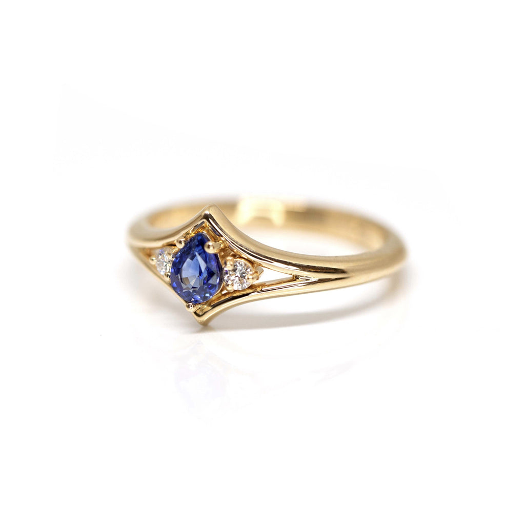 Bague de fiançailles avec saphir bleu et deux diamants extra brillants, en or jaune. Disponible à la bijouterie fine Ruby Mardi à Montréal.