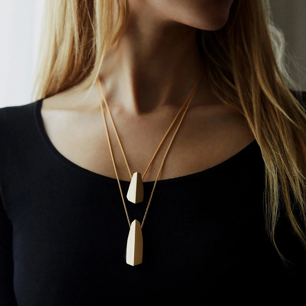 girl wearing two ballast pendant in vermeil gold made in montreal by bena jewelry at the best jeweler in montreal boutique ruby mardi on black background