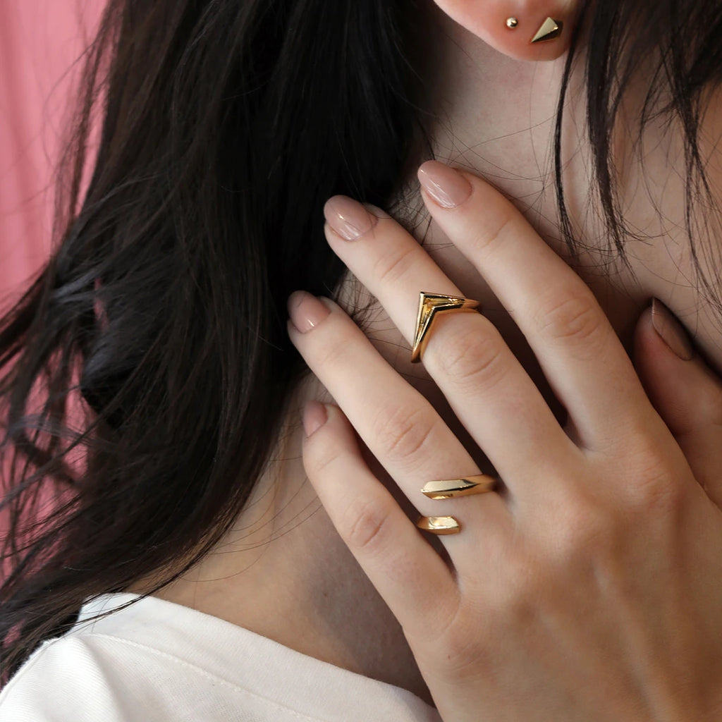 girl wearing gold ring rings white a white shirt and a pink background
