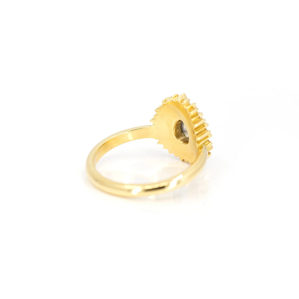 Back view of an 18-carat yellow gold ring. The body of the ring is mostly visible, and the back of the central gemstone, a salt-and-pepper diamond, can be seen, but the rest of Emily Gill's creation is not visible in the photo.