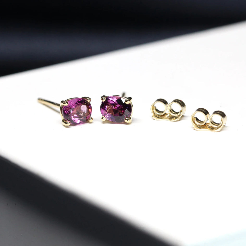 side view of purple garnet gold stud earrings fine designer custom made colored gemstone jewels for boutique ruby mardi in montreal little italy jeweler on a white and grey background