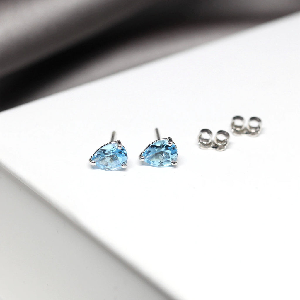 front view of blue topaz gemstone stud earrings minimalist style made in the best jewelry store montreal boutique ruby mardi finest canadian jewellery designer gallery in canada on white and grey background