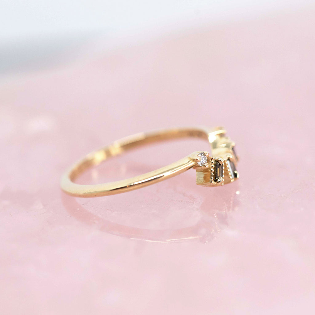 A dainty yellow gold wedding band with 3 champagne diamonds baguette cut photographed on rose quartz. Find it at high end jewellery store Ruby Mardi in Montreal.