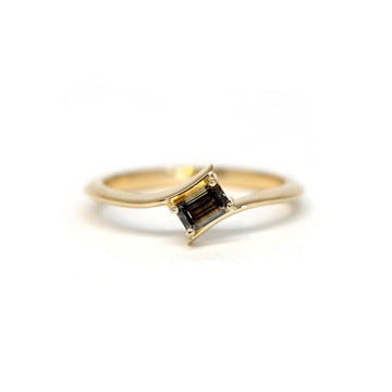 Twisted yellow gold engagement ring with an emerald cut dark brown diamond photographed on a white background. More one of a kind jewelry available at Ruby Mardi, a jewellery store in Montreal’s Little Italy.  Modifier le texte alternatif