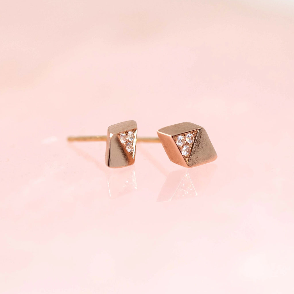 side view of edgy diamond rose gold minimalist earrings stud designer made in montreal at boutique ruby mardi liane vaz jewelry on a pink background