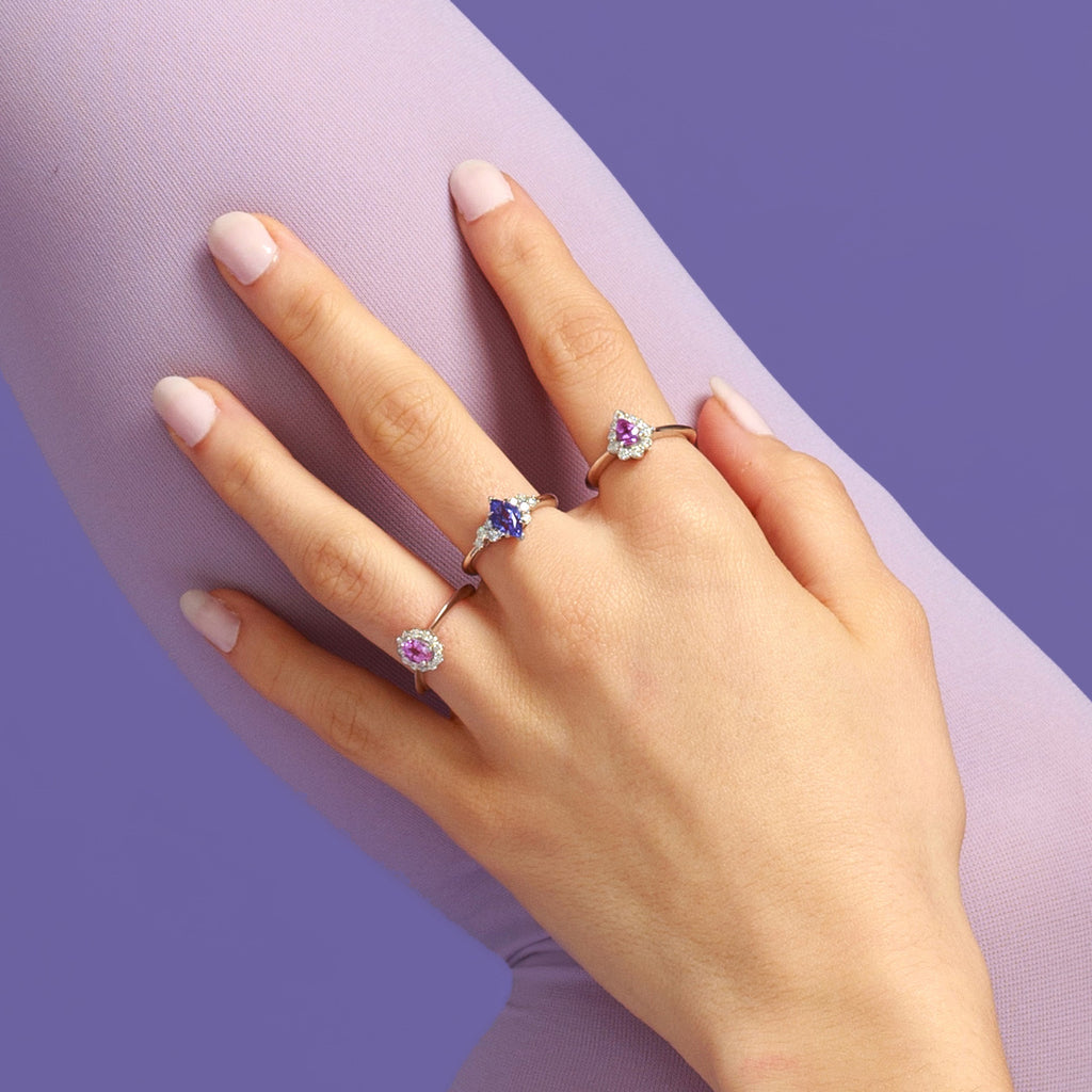 girl wearing a set of engagement ring with pink sapphire and tanzanite diamond bridal rings at boutique ruby mardi fine jeweller in montreal on purple background