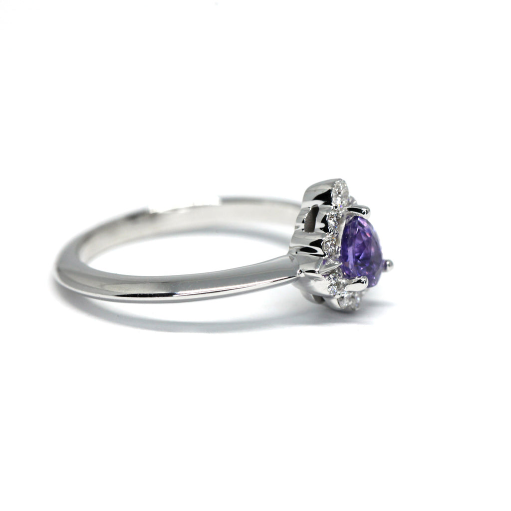 side view of a white gold purple sapphire natural colored gemstone and diamond halo on a custom made white gold engagement ring made in montreal by ruby mardi jeweller on a white background