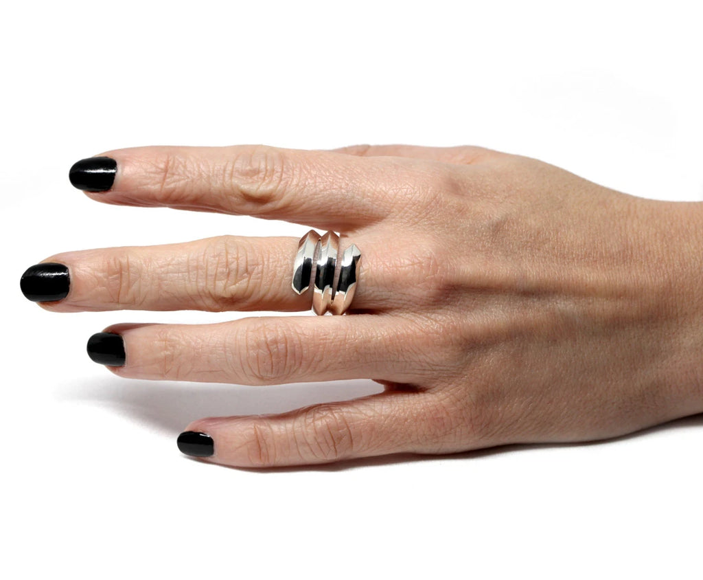 A lady’s hand wears a designer silver sterling ring made of three laces around the finger. Find more designer everyday jewelry and high end jewelry at Ruby Mardi, the only fine jewelry gallery in Montreal.