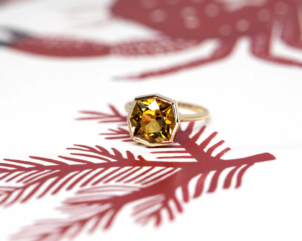 A ring from designer Bena Jewelry seen on a wallpaper. A statement ring featuring a big citrine set in 14 yellow gold with a refined design. Fine jewelry handmade in Montreal and available online for worldwide shipping. 