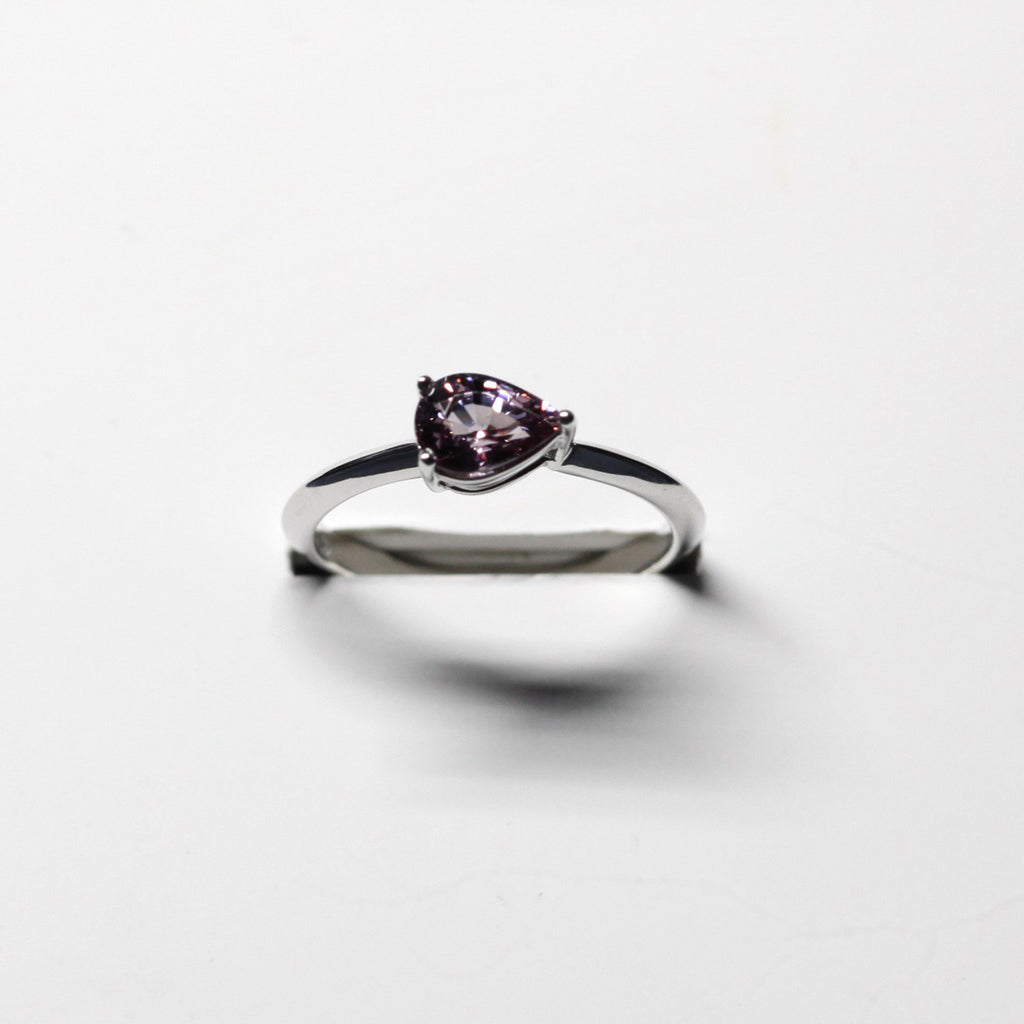front view of a pear shape malaya garnet purple colored gemstone engagement ring made in montreal by the bespoke jewelry designer boutique ruby mardi montreal on a white background