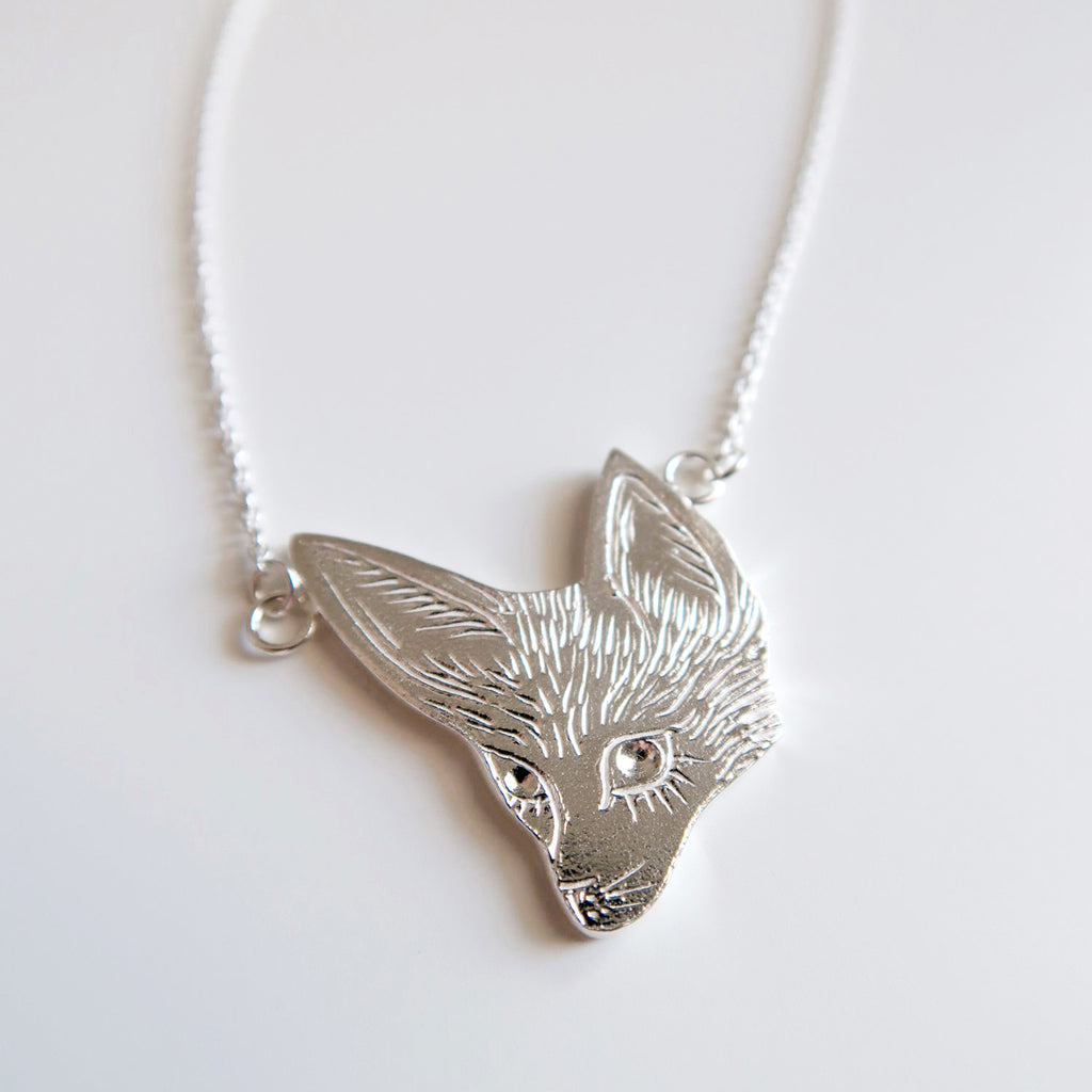 A wide-eyed, large-eared fennec fox silver fox pendant by Invidiosa Jewelry and available at Ruby Mardi in Montreal.