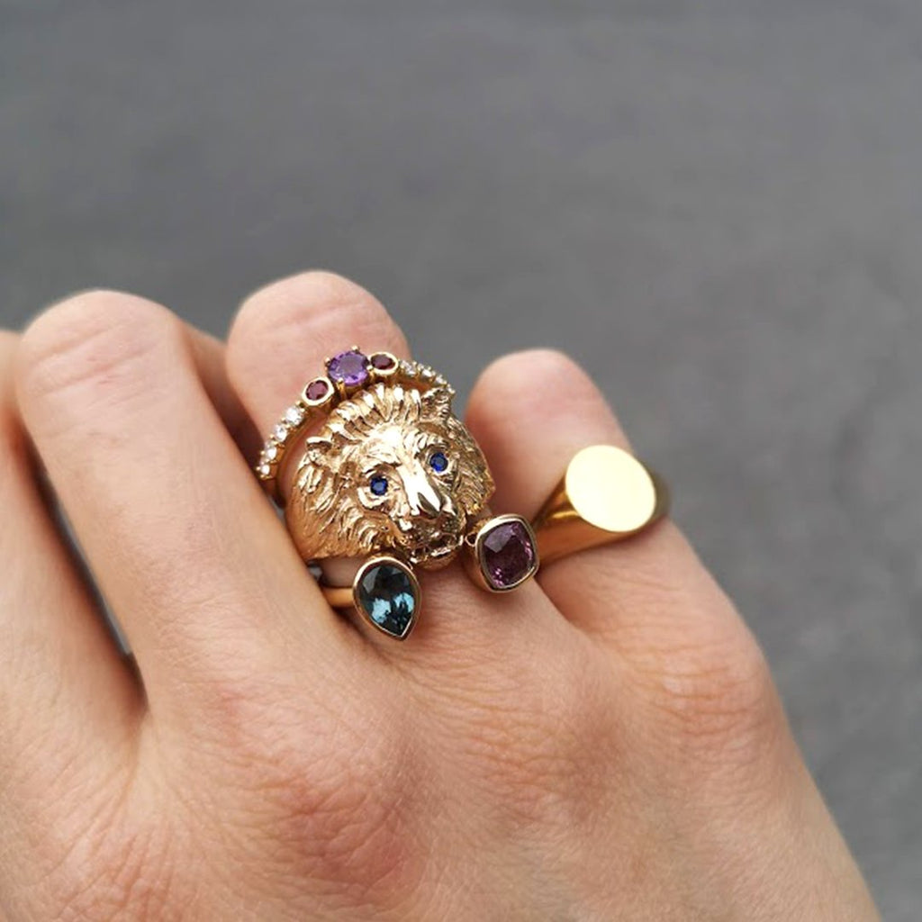 Close up on a hand wearing original gemstone gold rings. Amongst them, Gold lion head ring with blue sapphire eyes by jewellery designer Cecilia Lico. Her creations are available at Ruby Mardi, a luxury jewellery store located in Montreal's Little Italy.