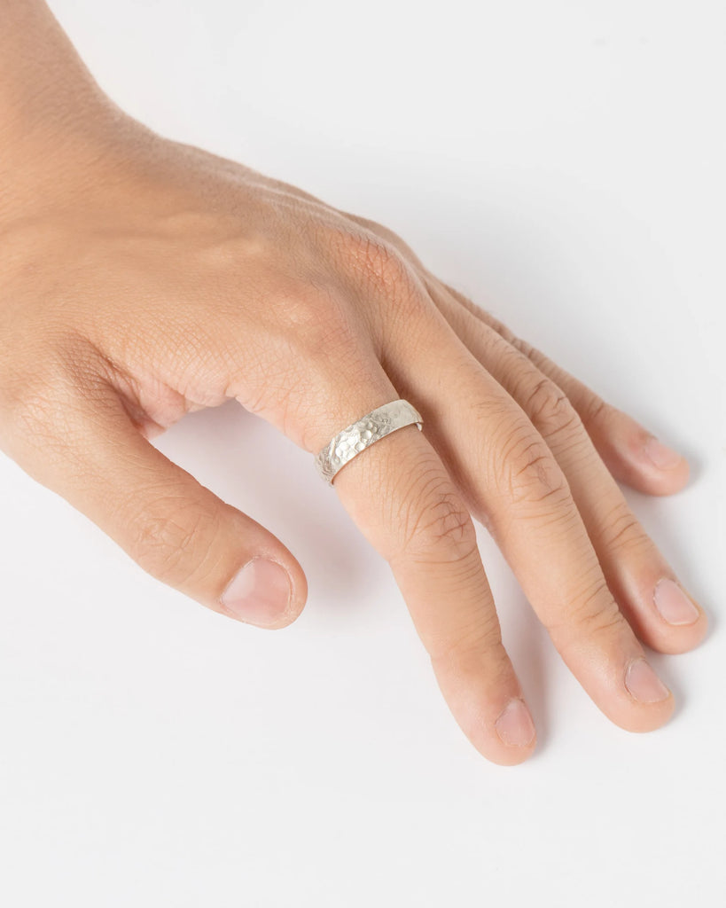 someone hand wearing hammered gold wedding ring made by artisan designer in montreal jeweler ruby mardi on a white background