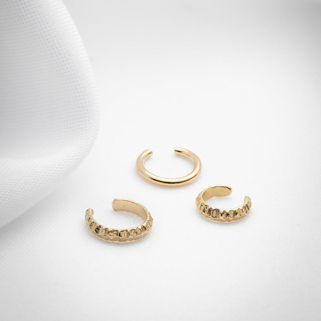 Three ear cuffs in gold vermeil shown on a white background, one slick and 2 with texture. Handmade in Montreal by jewelry brand Véronique Roy JWLS