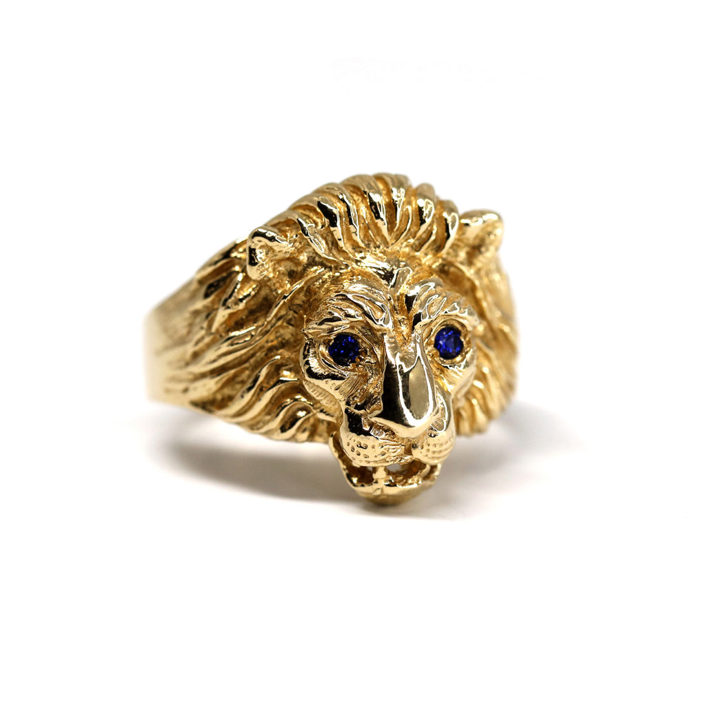 Photo de produit sur fond blanc d'une bague en or en forme de tête de lion et yeux en saphirs bleus par la créatrice de bijoux Lico Jewelry. Ses créations sont disponibles chez Ruby Mardi, une bijouterie de luxe située dans la Petite Italie de Montréal.