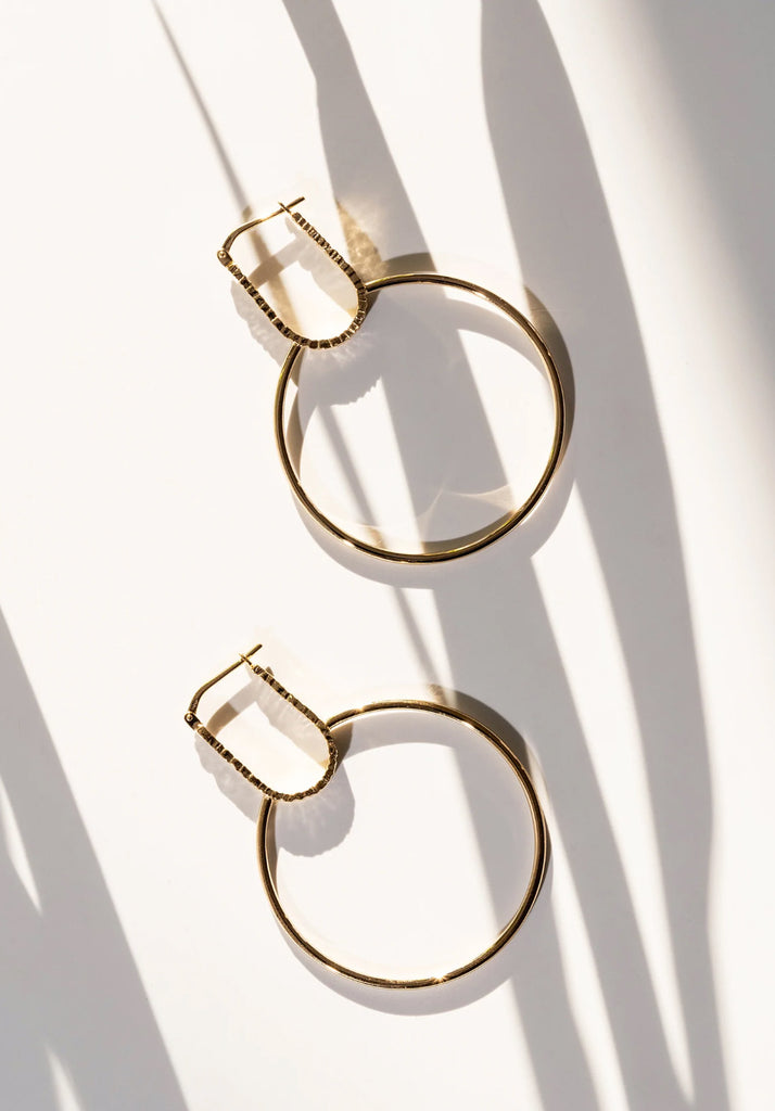 large hoops earrings made in vermeil gold by artisan jewellery designer veronique roy on a white bakcground and shadows
