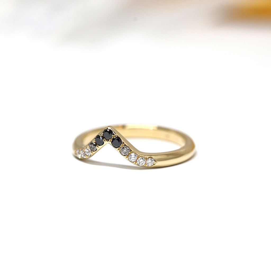 A curved band in yellow gold featuring eleven diamonds in a gradation from white to black. A wedding band handcrafted by Yuliya Chorna, available at Ruby Mardi, a fine jewelry store showcasing the work of talented Canadian jewelry designers.